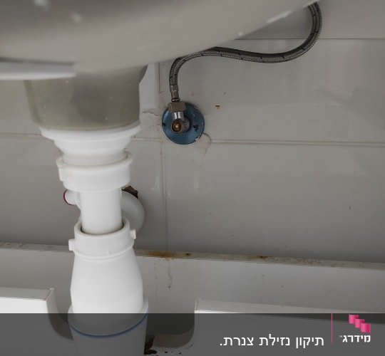 צינור ניקוז לבן מתחת לכיור עם חיבור מתכת